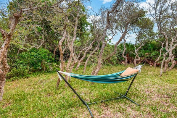 A hammock set up in a grassy area with trees in the background. - Tuckers Hideaway at Seagate (St. Augustine)