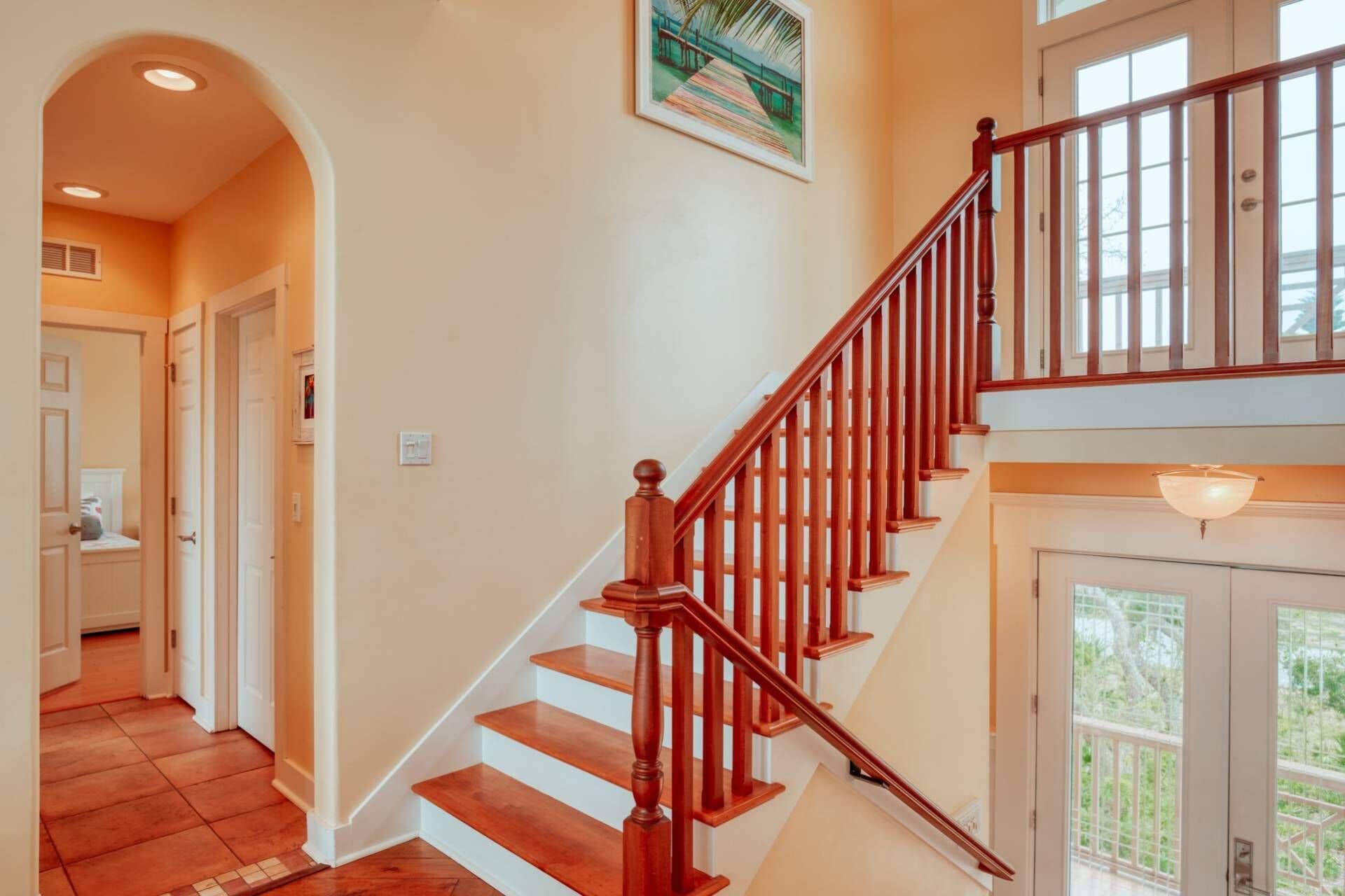 A wooden staircase with a handrail, leading to a balcony with a glass door.