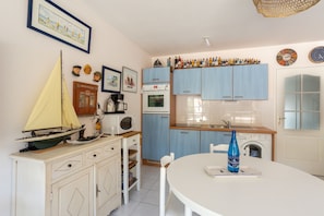 A kitchen with blue cabinets, a white table, and a sailboat model.