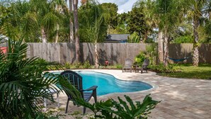 Un giardino con piscina, mobili da patio e una recinzione in legno.
