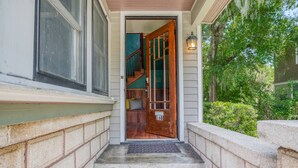 L'ingresso di una casa con una porta in legno, una scalinata in cemento e una cassetta delle lettere.