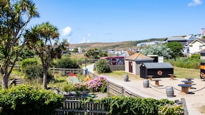 A coastal area with a small wooden structure, possibly a café or restaurant, with outdoor seating and a sign indicating a no-smoking area. - Baywatch Sands (Wadebridge)