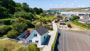 A coastal property with a parking area, a white building with a sloped roof, and a view of the beach and ocean. - Baywatch Sands (Wadebridge)