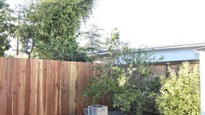 A wooden fence, a concrete planter, and various shrubs in a garden area. - Sunshine on Sylvan! (Los Angeles)