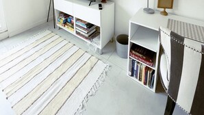 A modern, minimalistic room with a white console table, a flat-screen TV, a lamp, a small plant, and a bookshelf. - Sunshine on Sylvan! (Los Angeles)