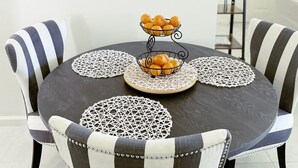A dining area with a round table, striped chairs, a wall clock, and a fruit basket. - Sunshine on Sylvan! (Los Angeles)