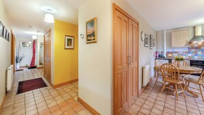 A hallway leading to a kitchen with a tiled floor, wooden doors, and a dining area with chairs. - 3 bedroom accommodation in Cowshill, near Alston (Cowshill, near Alston)