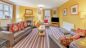 A living room with a sofa, armchair, TV, fireplace, and a striped rug. - 3 bedroom accommodation in Cowshill, near Alston (Cowshill, near Alston)