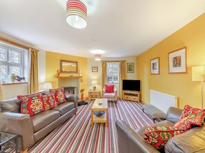 A living room with a sofa, armchair, TV, fireplace, and a striped rug. - 3 bedroom accommodation in Cowshill, near Alston (Cowshill, near Alston)