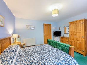 Quarto com uma cama, televisão, guarda-roupa de madeira e radiador.
