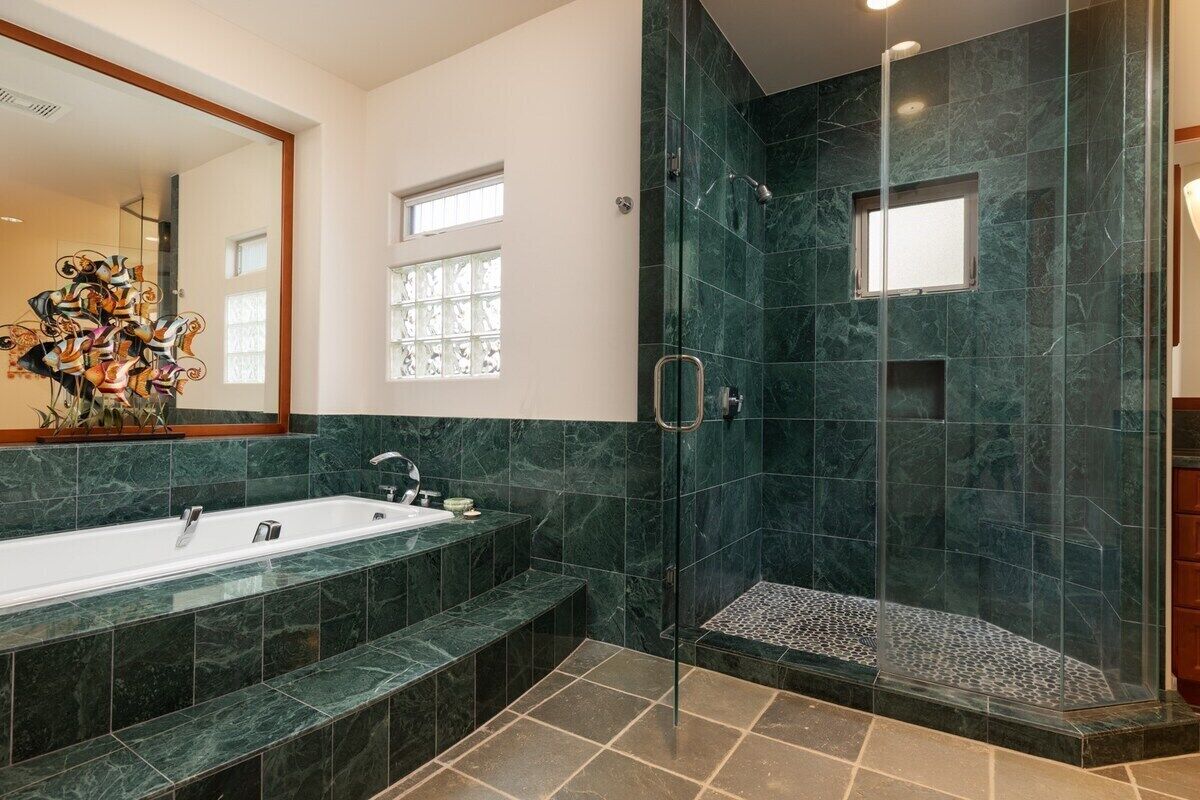 Un bagno moderno con una vasca da bagno grande, una cabina doccia in vetro e un pavimento in marmo.