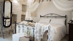 Une chambre à coucher avec un lit, une table de chevet, un miroir et un arbre décoratif.