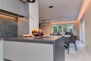 Una cocina moderna con una isla central, zona de comedor con sillas y un amplio ventanal que proporciona luz natural.