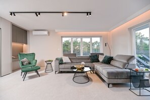 A modern living room with a grey sectional sofa, a green armchair, and a round coffee table.