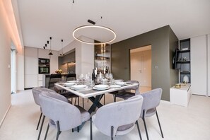 A modern dining area with a rectangular table set for six, surrounded by grey upholstered chairs.