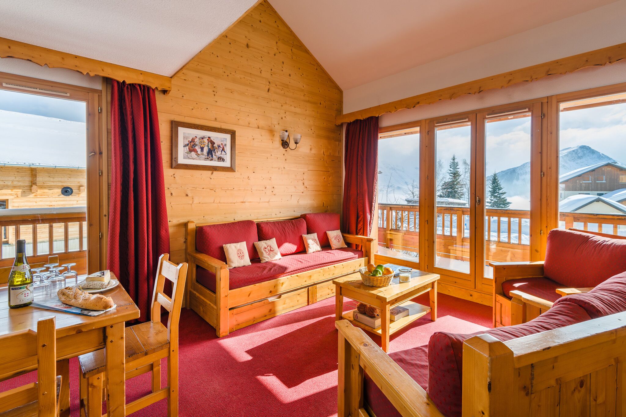 A wooden cabin interior with a sofa, dining table, and chairs.
