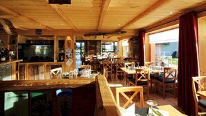 A rustic wooden interior with a bar area, dining tables, and chairs.