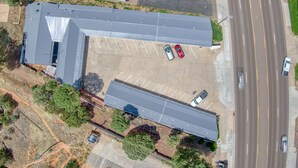 Luchtbeeld van een gebouw met een parkeerplaats, een omliggende weg en meerdere voertuigen.