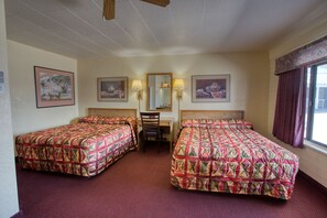 A hotel room with two beds, a desk, and a chair. - Kiva Motel (Show Low)