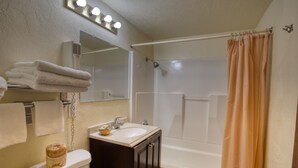 Een badkamer met toilet, wastafel, spiegel en douche.