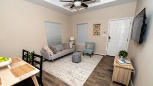 A compact living space with a dining area, sofa, ottoman, and a small table with a bowl of fruit. - Gorgeous Pet Friendly Townhome: Clean and Spacious With Private Terrace! (Edinburg)