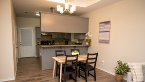 A compact kitchen with a dining area, wooden flooring, and a small living space with a sofa and a plant. - Gorgeous Pet Friendly Townhome: Clean and Spacious With Private Terrace! (Edinburg)