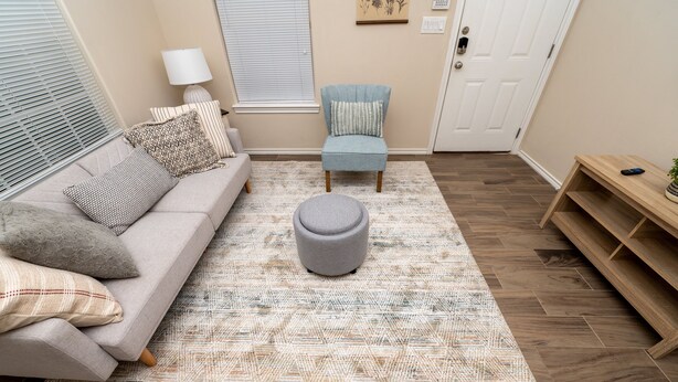 A living room with a sofa, ottoman, and chair, a patterned rug, and a wooden floor. - Gorgeous Pet Friendly Townhome: Clean and Spacious With Private Terrace! (Edinburg)