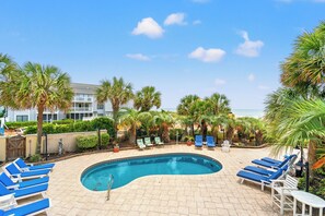 A swimming pool with lounge chairs and palm trees.