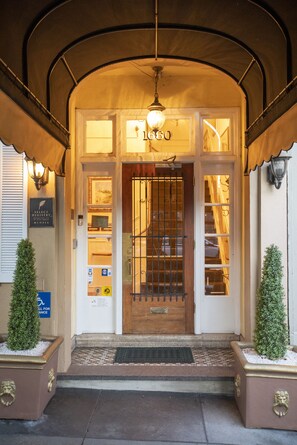L’entrée d’un hôtel, avec une plaque portant le numéro 1660, une porte grillagée et un auvent au-dessus de l’entrée.