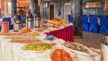 A buffet with various food items and a seating area with blue chairs.