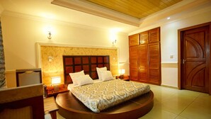 A bedroom with a large bed, wooden wardrobe, and a round seating area. - FELICIA HÔTEL (Yaoundé)