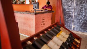 A bar area with a counter, bottles of wine, and a person working behind the counter.