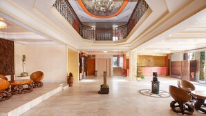 A spacious lobby with a high ceiling, a central staircase, and a reception desk. - FELICIA HÔTEL (Yaoundé)