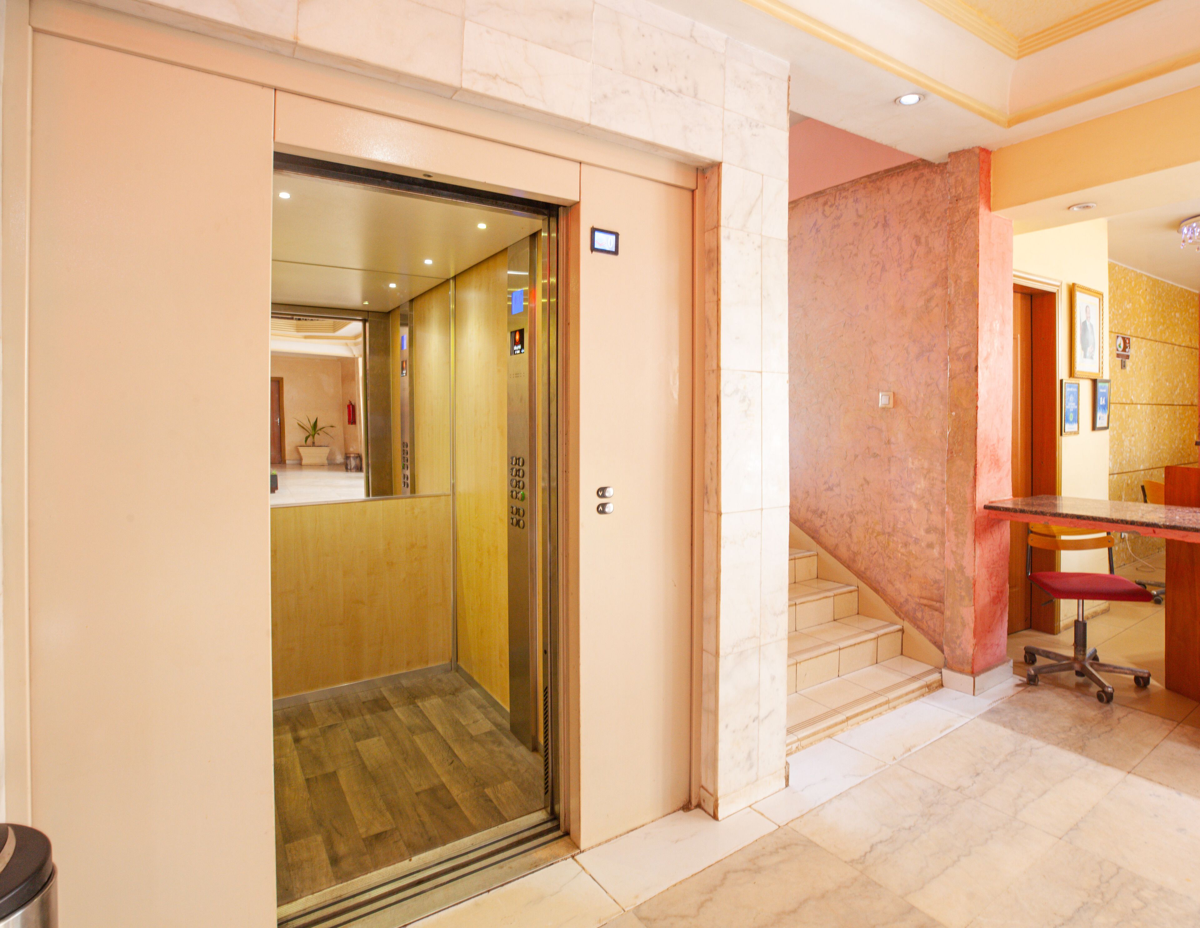 An elevator with a wooden interior and a marble floor.