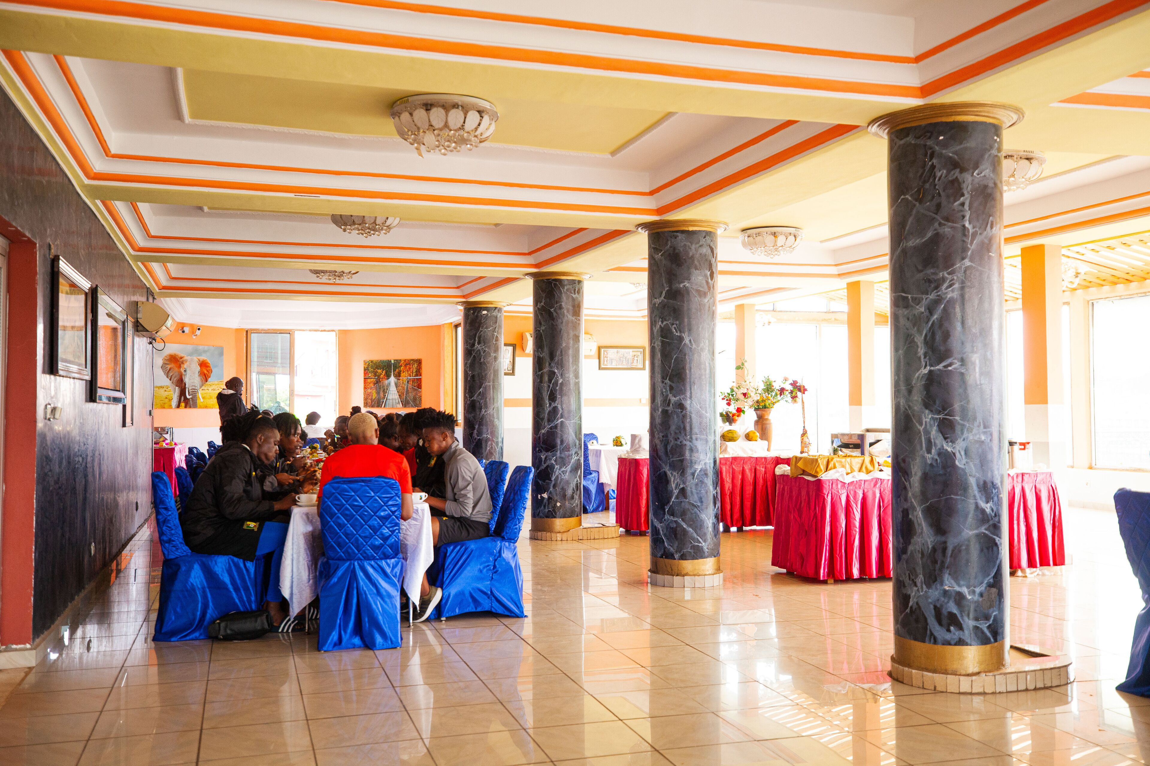 Un vaste hall agrémenté de colonnes en marbre, de sièges rembourrés en tissu bleu et de nappes rouges.