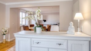 A modern kitchen with white cabinets, a dining area with wooden chairs, and a white decorative Buddha statue. - The spacious vacation apartment for 9 people is ideal for excursions. (Thale/OT Neinstedt)