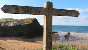 A wooden signpost with directions to Salcombe and Bantham, indicating distances of 8 miles and 4 miles respectively.