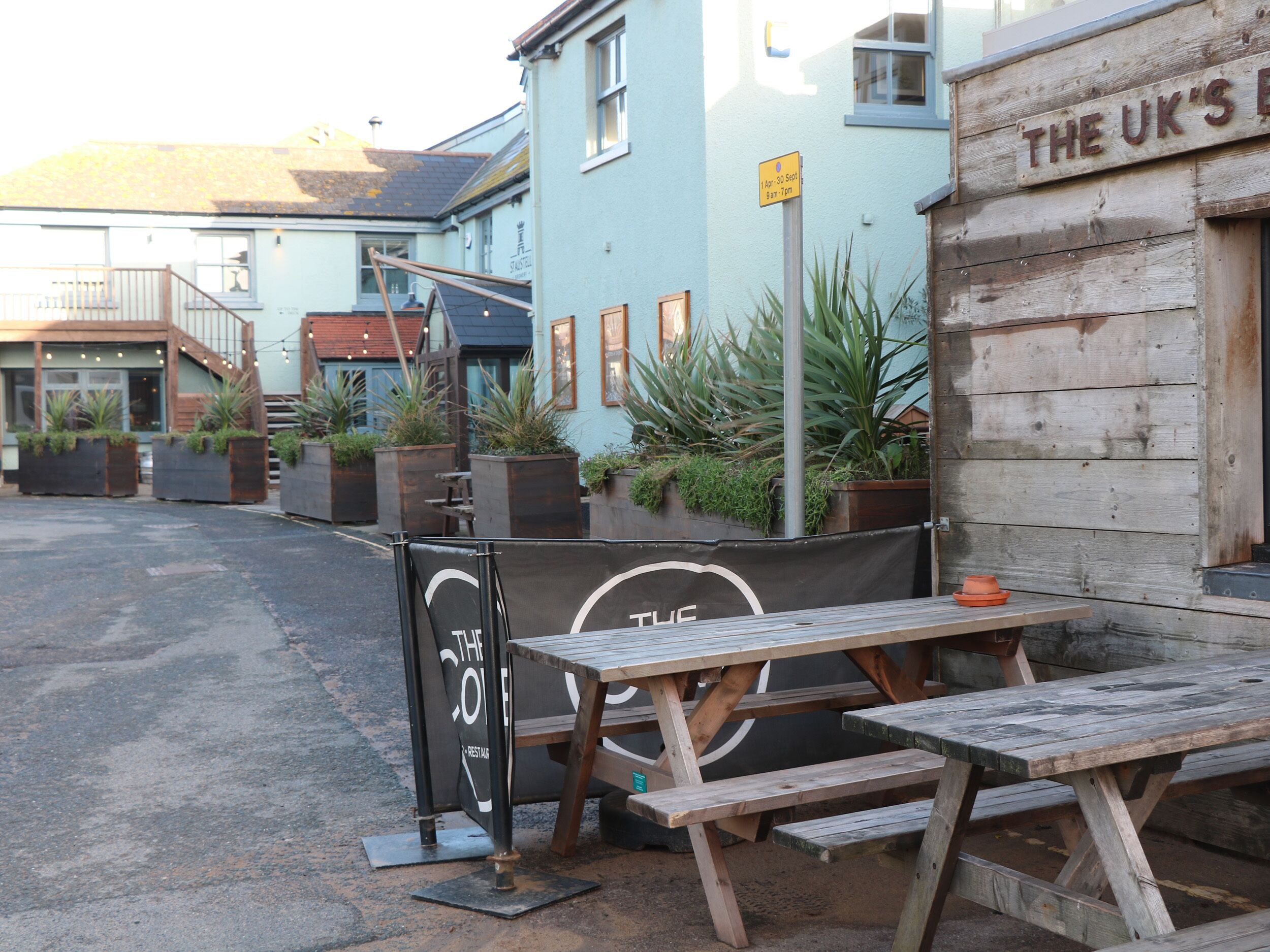 A wooden table and benches outside a building with a sign reading "THE UK'S".