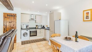 A compact kitchen with a dining area, a washing machine, a microwave, and a refrigerator. - Claro Cottage - UK37450 (Pateley Bridge, near Harrogate)