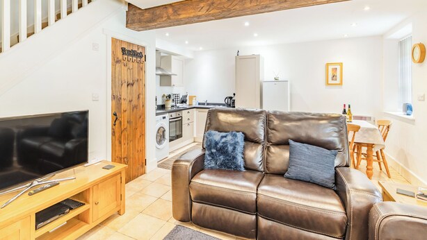 A living room with a brown leather sofa, wooden entertainment unit, and a TV. - Claro Cottage - UK37450 (Pateley Bridge, near Harrogate)