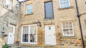 A stone building with two ground-floor doors and windows, a small entrance with steps, and a potted plant. - Claro Cottage - UK37450 (Pateley Bridge, near Harrogate)