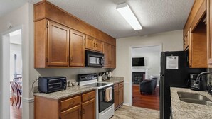 Une cuisine avec des meubles de rangement en bois, un four à micro-ondes, un grille-pain et un réfrigérateur.