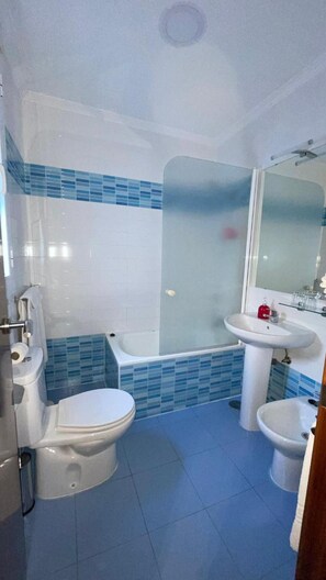 Een badkamer met toilet, bad en twee wastafels.