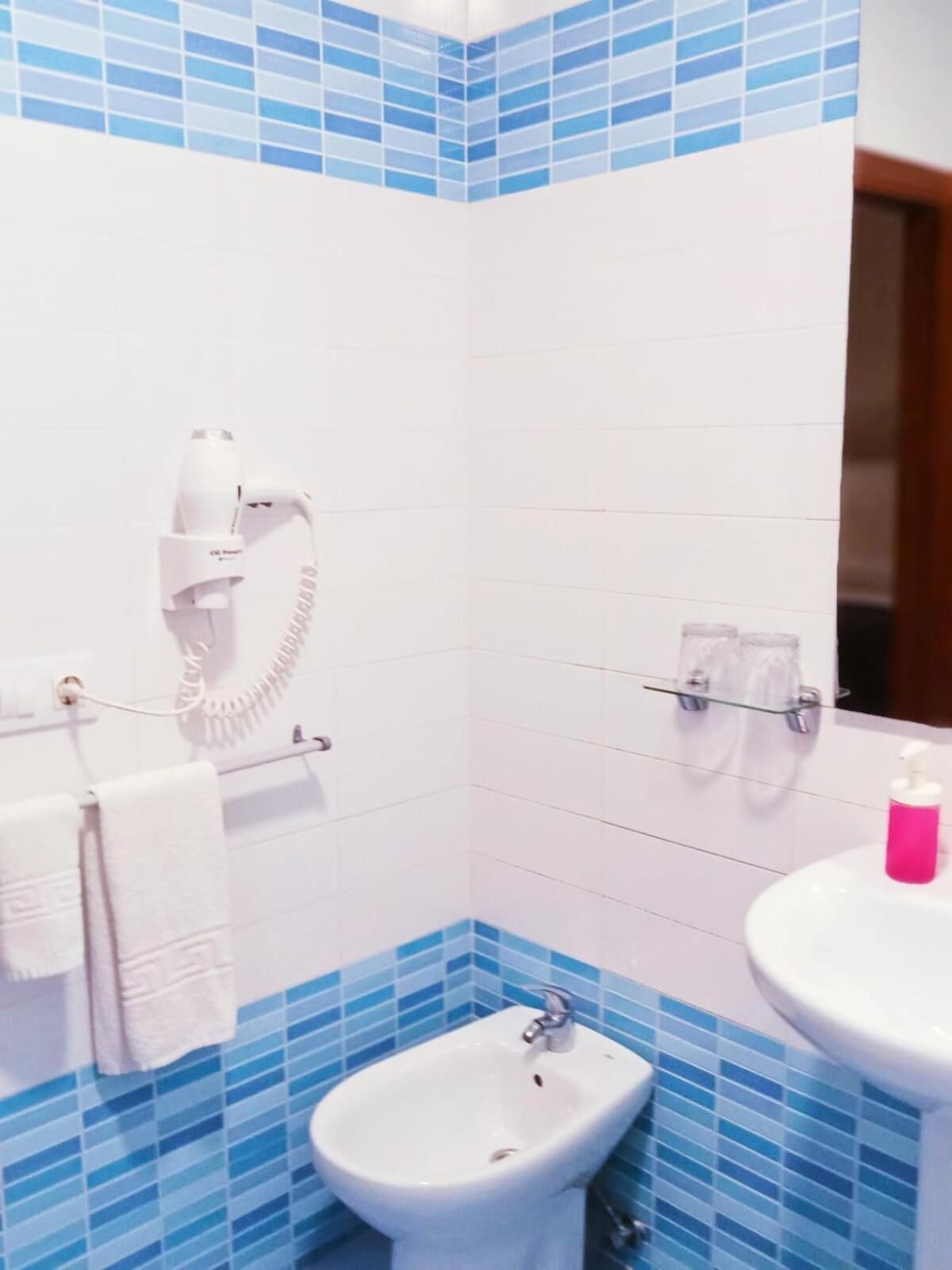 A bathroom with a bidet, a toilet, a sink, and a telephone.