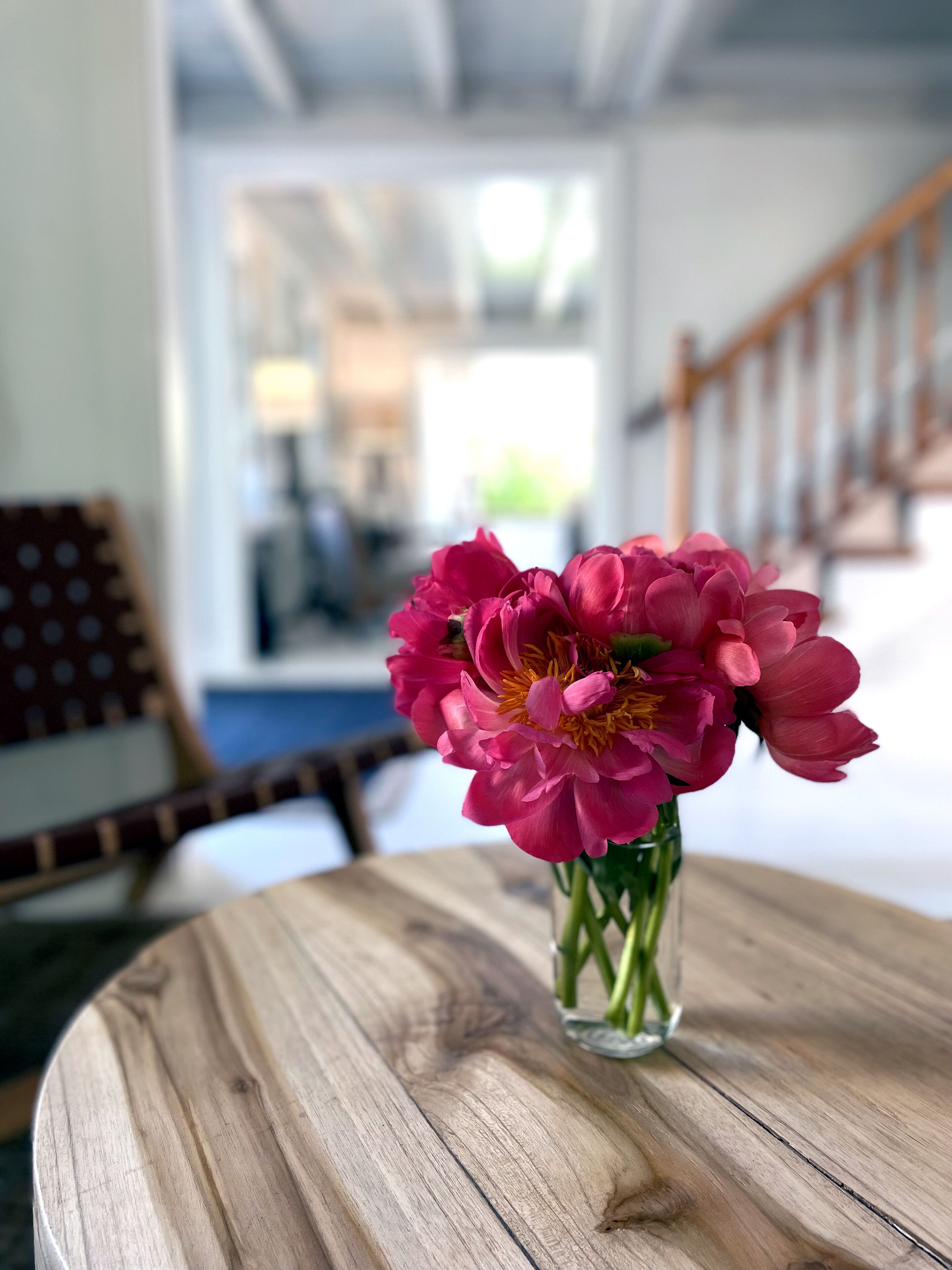 Un tavolo di legno con un vaso di vetro trasparente pieno di fiori rosa.