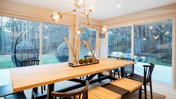 Un espace repas moderne avec une table en bois, des chaises noires et un luminaire suspendu.