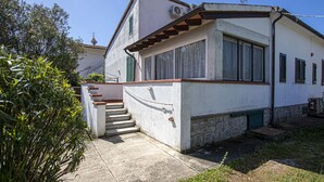 A two-story house with a stone foundation, a small front porch, and a staircase leading to the entrance. - CASA GINESTRA - GINESTRA 2 (Campo nell'Elba)