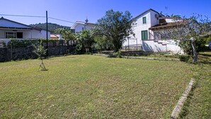 A residential area with houses, a grassy yard, and a stone wall. - CASA GINESTRA - GINESTRA 2 (Campo nell'Elba)