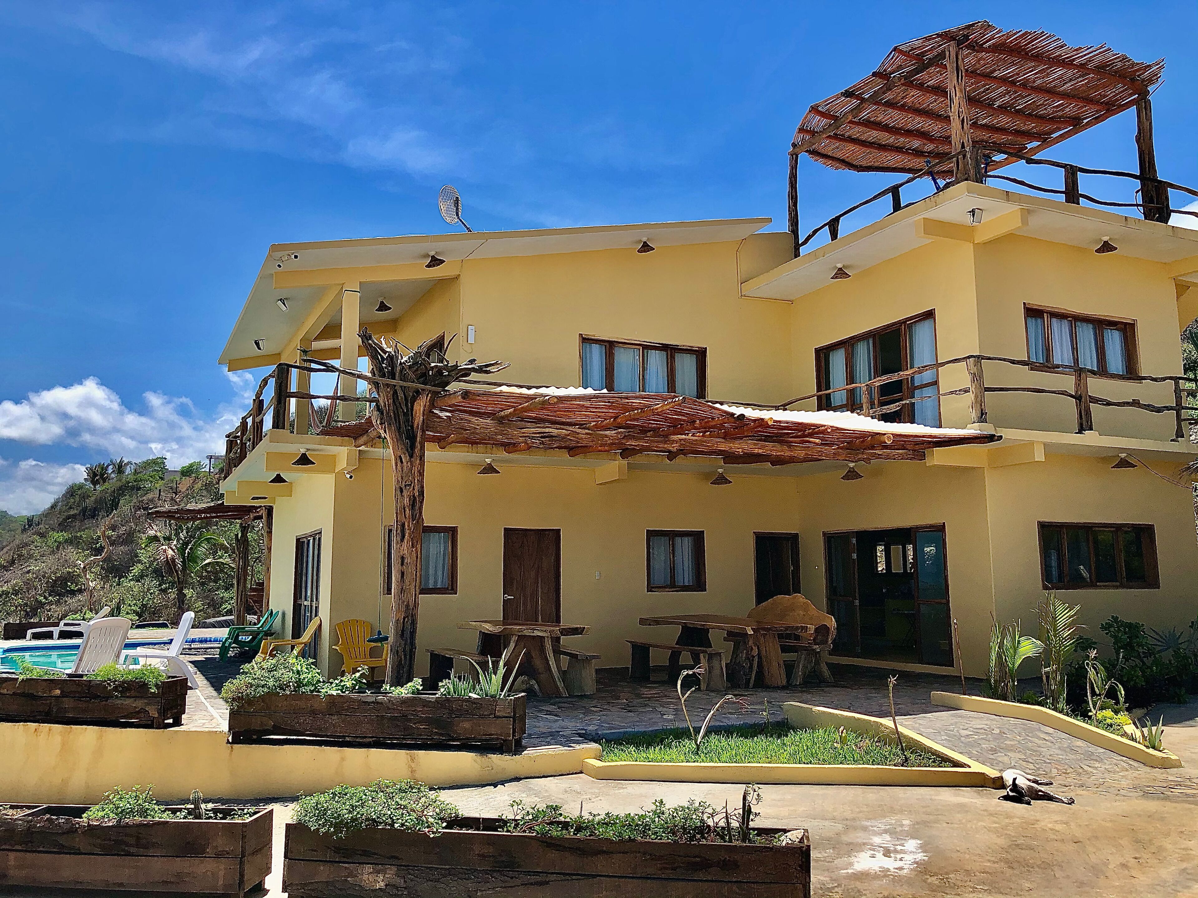 Un edificio di due piani con un balcone, posti a sedere all'aperto e una zona piscina.
