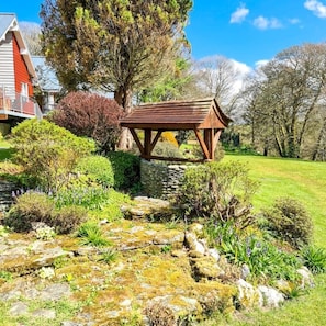 Escape to a serene garden oasis with a charming gazebo surrounded by lush greenery and a meandering stone pathway.